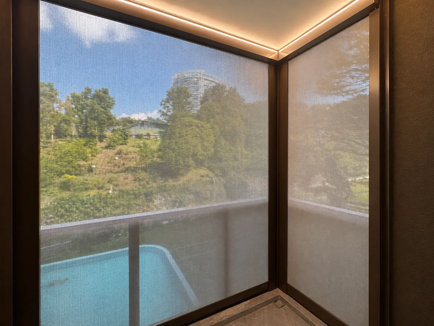 Outdoor zip blinds filtering sunlight beside a pool view